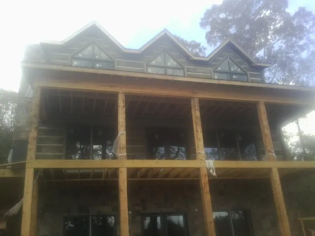 Dormers and porch framing on a large log home under construction — Roof Coating work by our crew in La Vergne