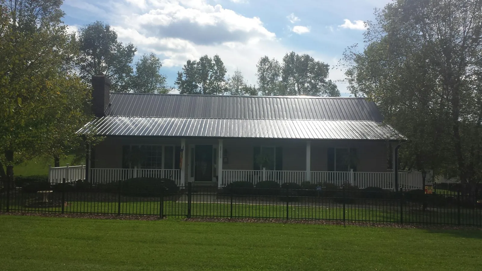 Gray metal roof on a brick ranch with a full width front porch — Gutter Guard Installation work by our crew in La Vergne