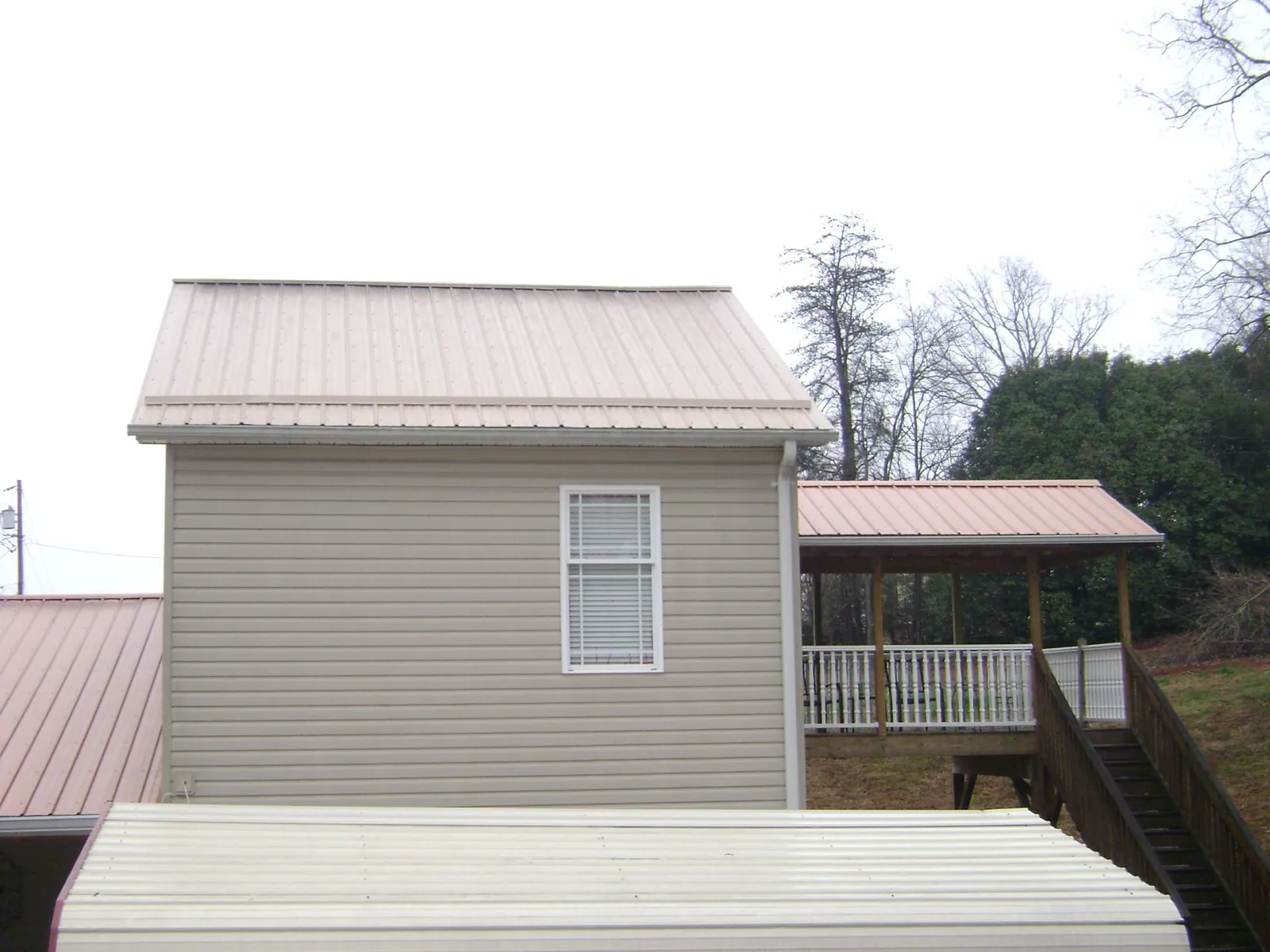 Tan metal roofs on a two story addition and attached porch, from a Roof Replacement job in La Vergne